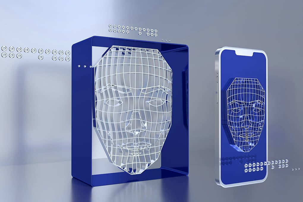 A digital wireframe face design appears on a blue block and a smartphone screen, symbolizing facial recognition technology used to protect against stolen identity